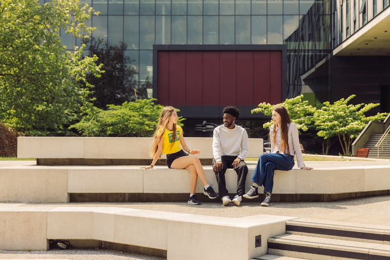 Three students sitting together in quadrangle