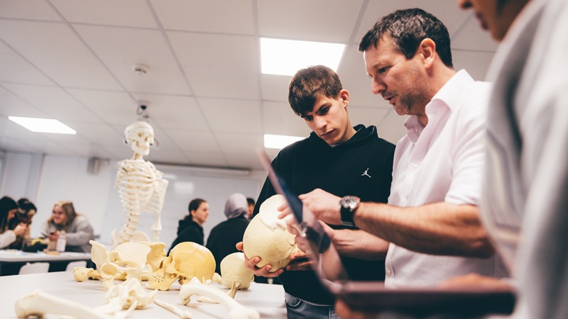 Anthropology professor talking to students with skeletal bones