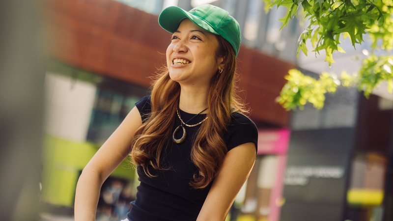 Student wearing a green cap outside on campus