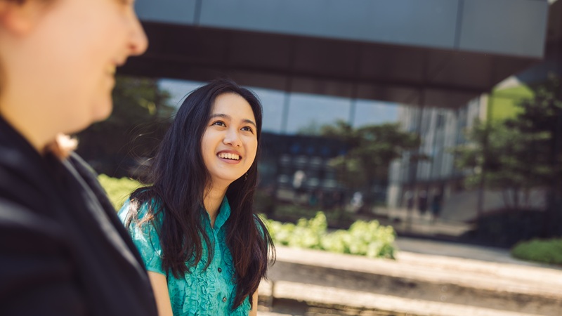 Student wearing a green cap outside on campus