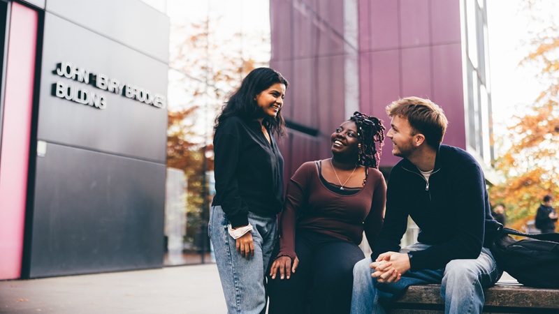 Three student outside on campus having a conversation