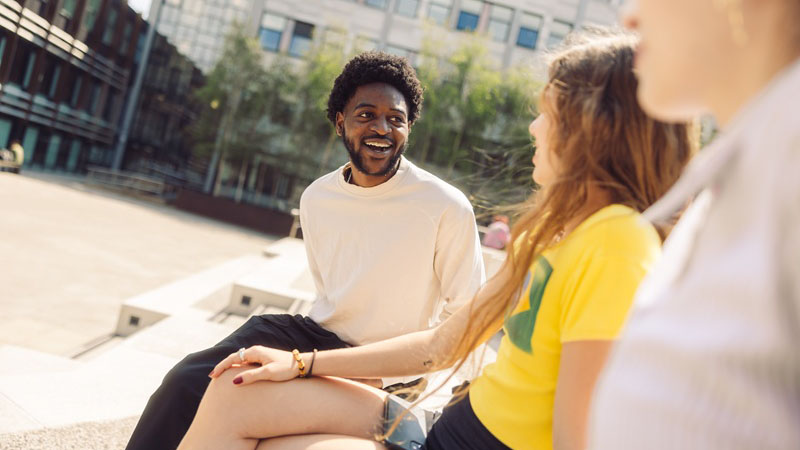 Three students sitting in a line talking to each other