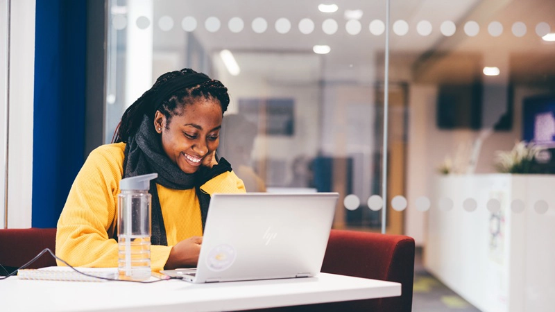 Smiling female student working on a laptop 