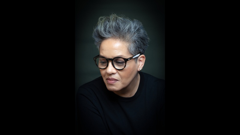 Portrait of author Kit de Waal wearing glasses and looking down.