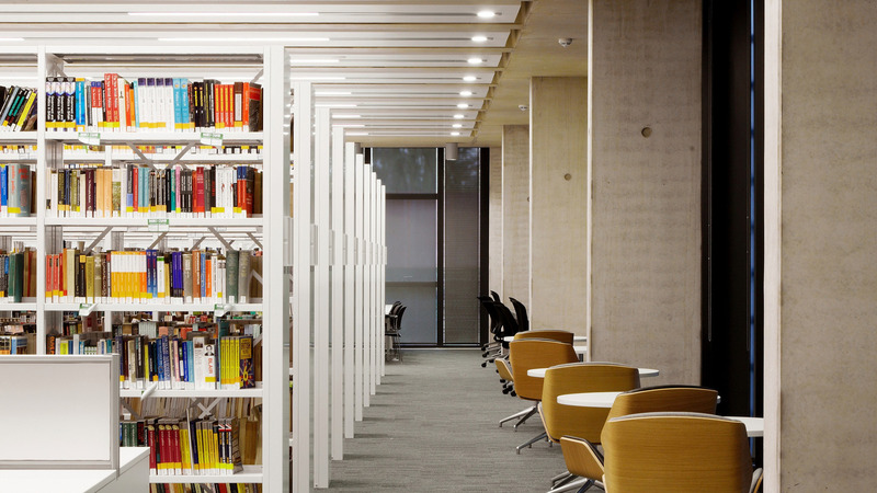 Rows of library shelving next to round tables and chairs