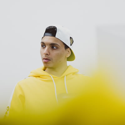 A male student wearing a white cap and yellow sweatshirt