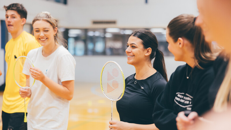 Students smiling with badminton rackets 