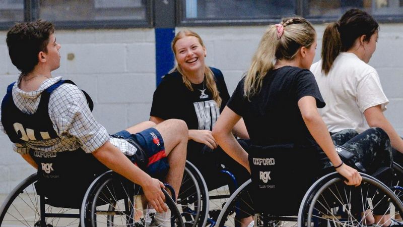 Students smiling enjoying wheelchair basketball 