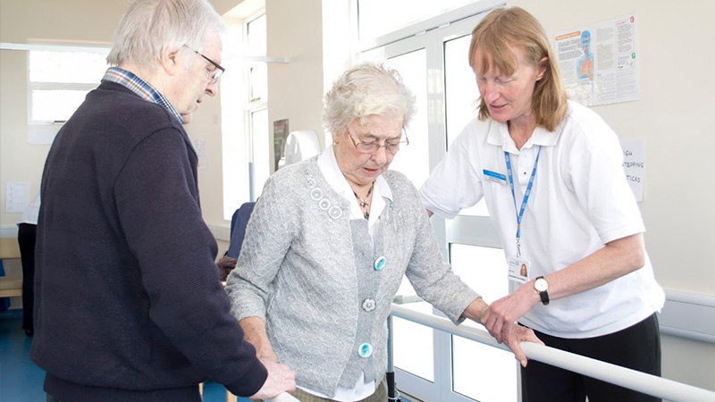 healthcare professional aiding elderly patient to walk