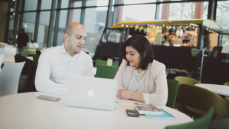 Two creative writing students looking at a laptop