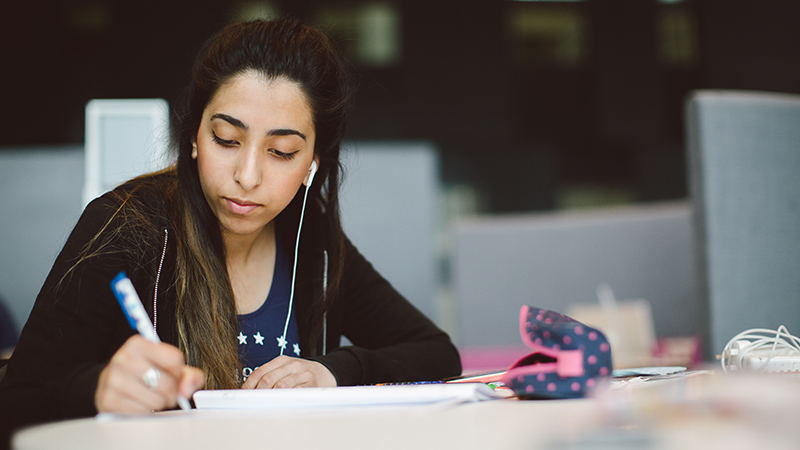 Photo of female student writing in JHB building at Brookes