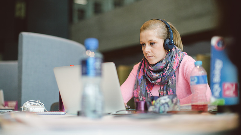 Female student studying on a laptop with headphones on
