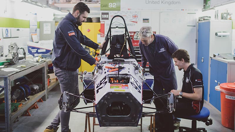 Students working on a motorsport car in garage