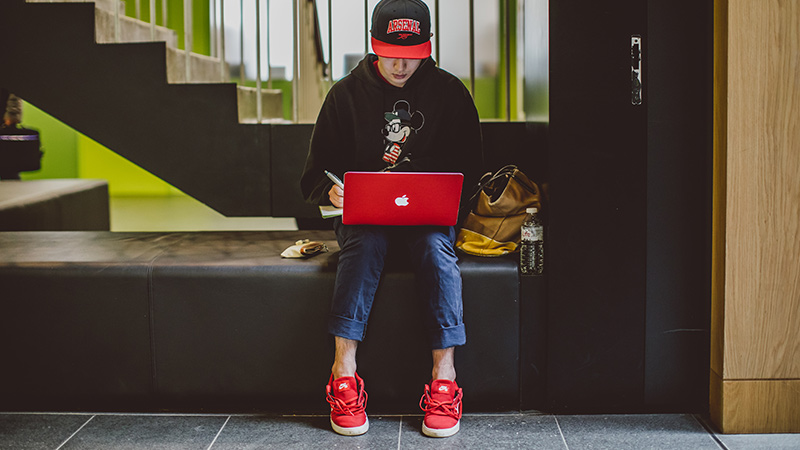 Student using red laptop in Brookes building