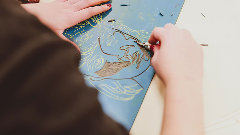 Student carrying out a linocut on campus in a studio