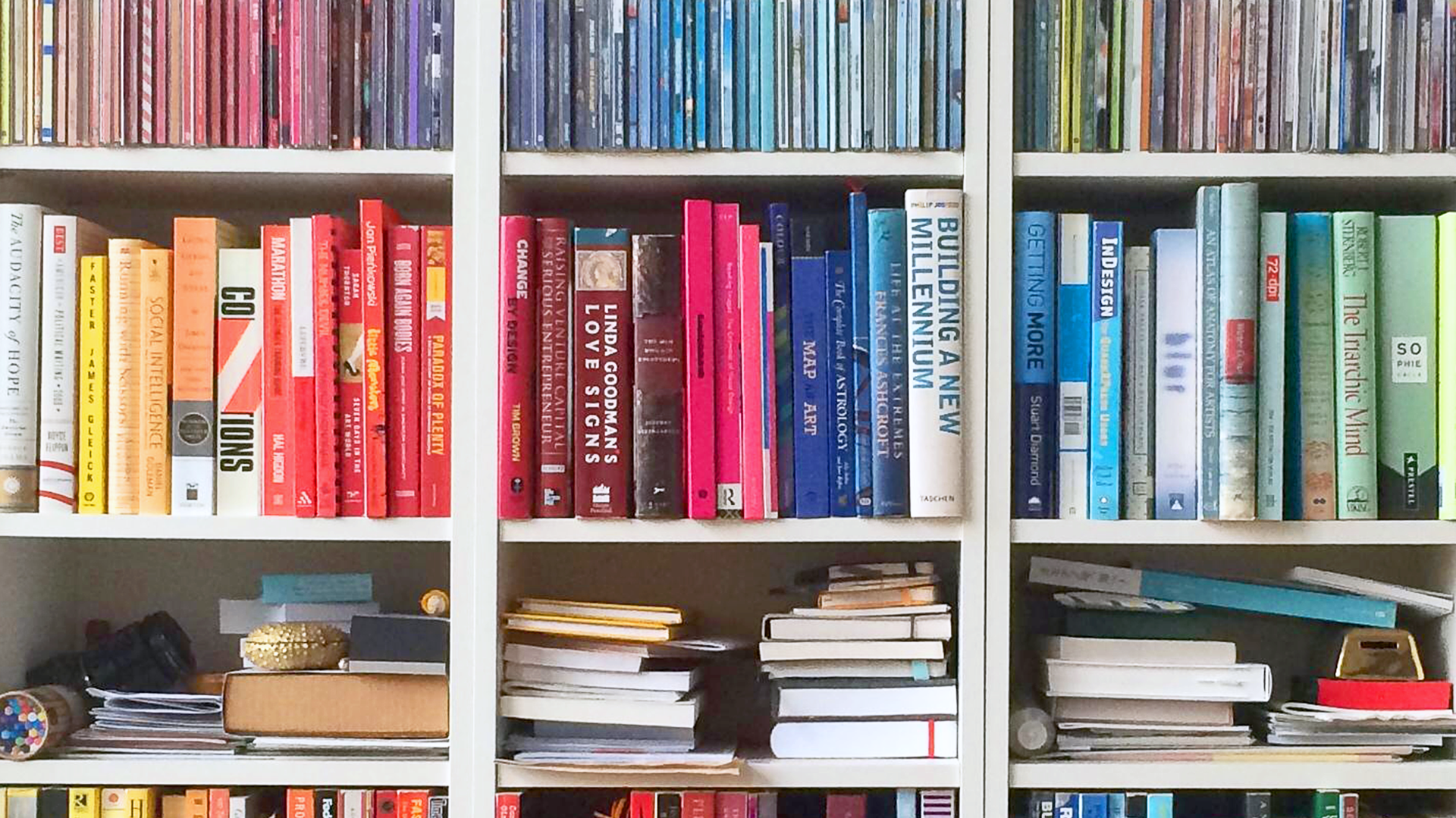 A bookcase, with the books arranged into coloured groups