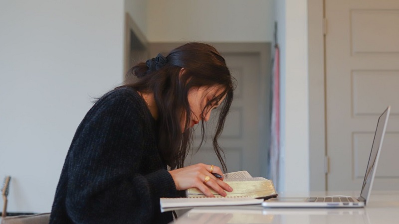 Student checking a book whilst studying