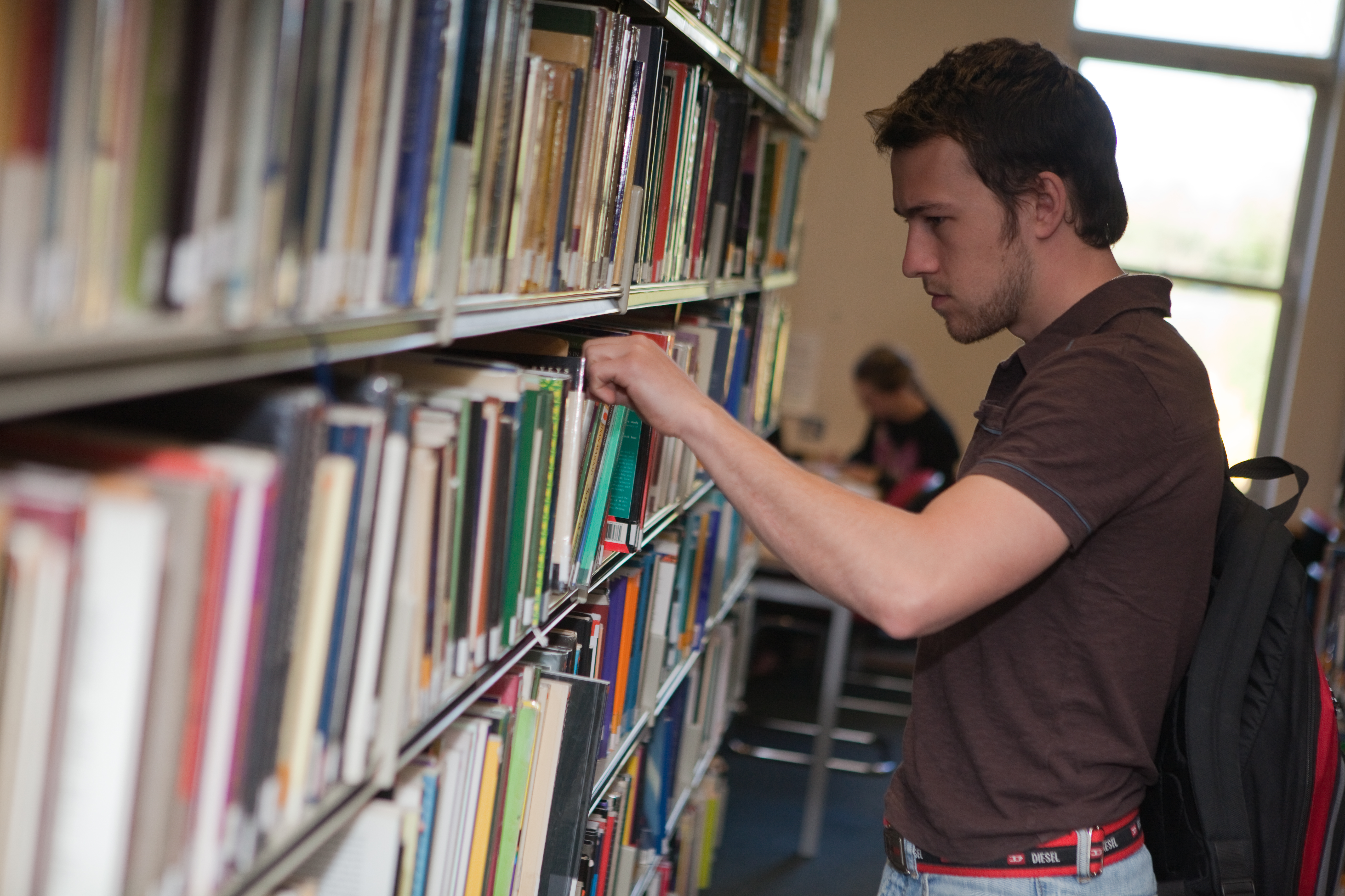 A male student browsing the library stacks