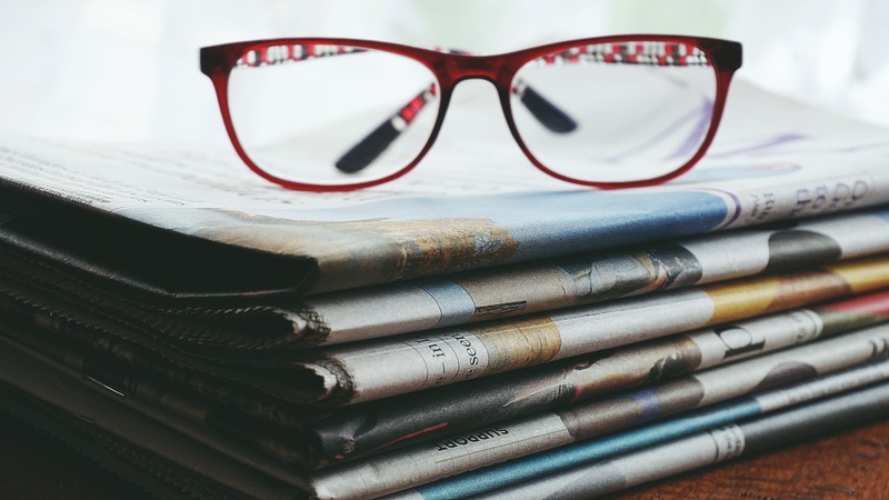 Stack of newspapers with a pair of spectacles resting on top