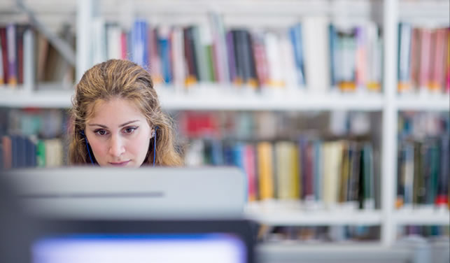 student looking at monitor in library