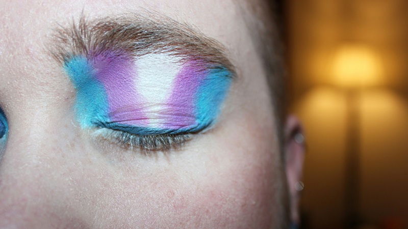 close up of eye with trans colours of sky blue, purple, white, purple, sky blue eyeshadow on the ciosed eyelid
