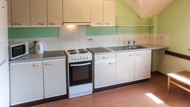 Kitchen counters along one one with freestanding oven, microwave and kettle.