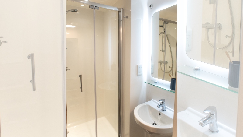 Modern en suite shower cubicle, basin and mirror.