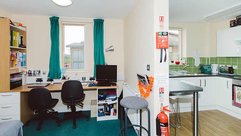 Study desk in front of window and kitchen with breakfast bar. Wall divider to separate the two areas.