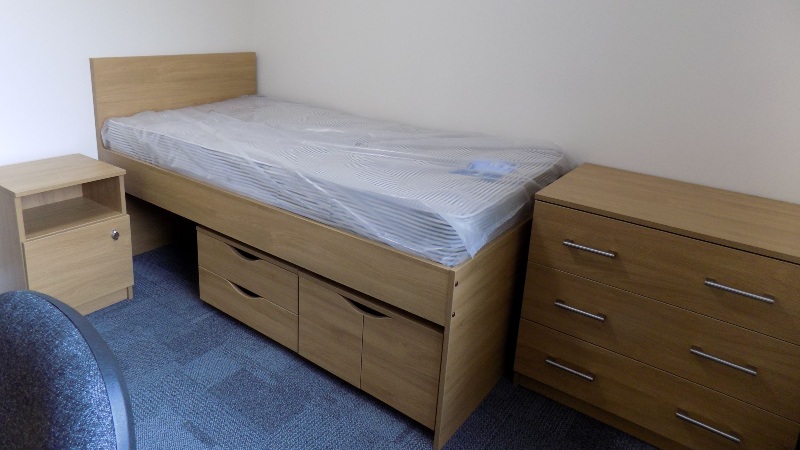 Single bedroom - bed with under bed storage, bedside table and chest of drawers. Blue carpet.