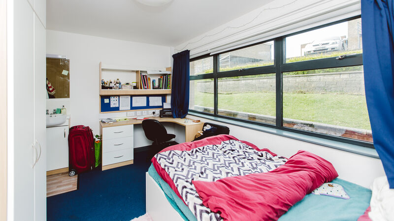 Spacious bedroom with small double bed, large windows and study desk.