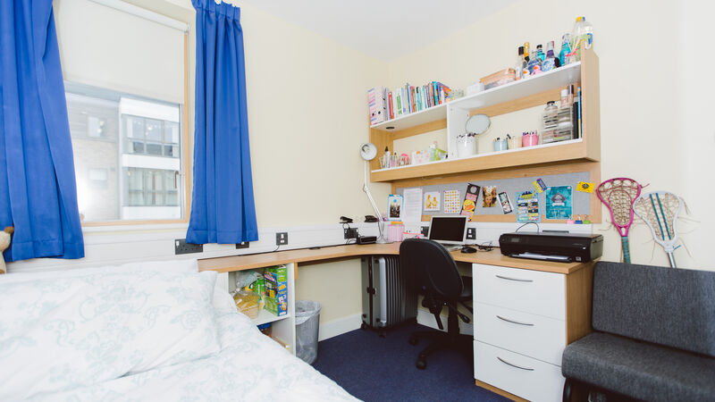 Wrap around study desk with window, shelving, desk chair and small seat.