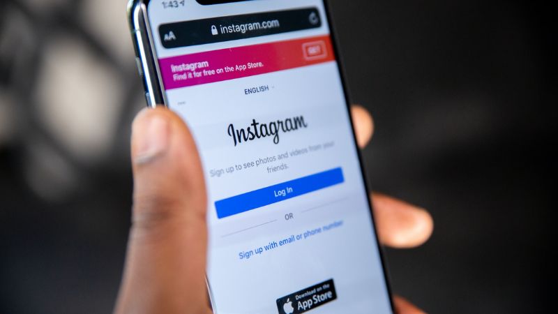 A hand holding a smartphone showing the Instagram login page.