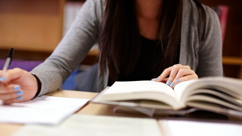 Student browsing a book and making notes
