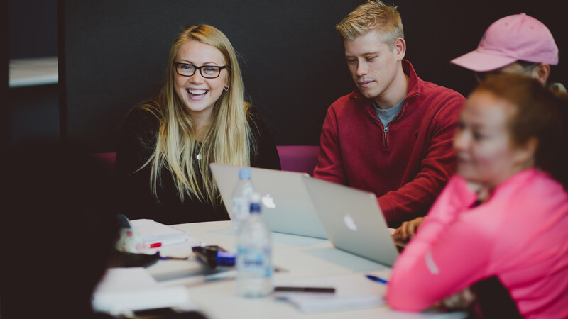 Four students working on laptops at a table