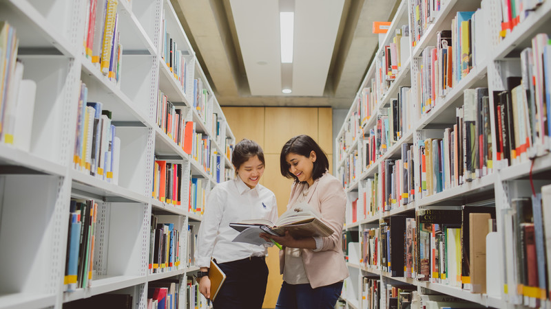 Two students standing in the library