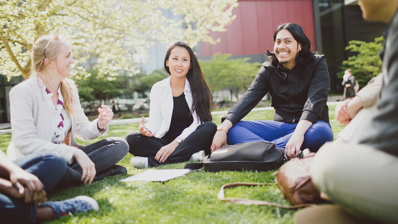 group of smiling students sitting on the grass at Brookes