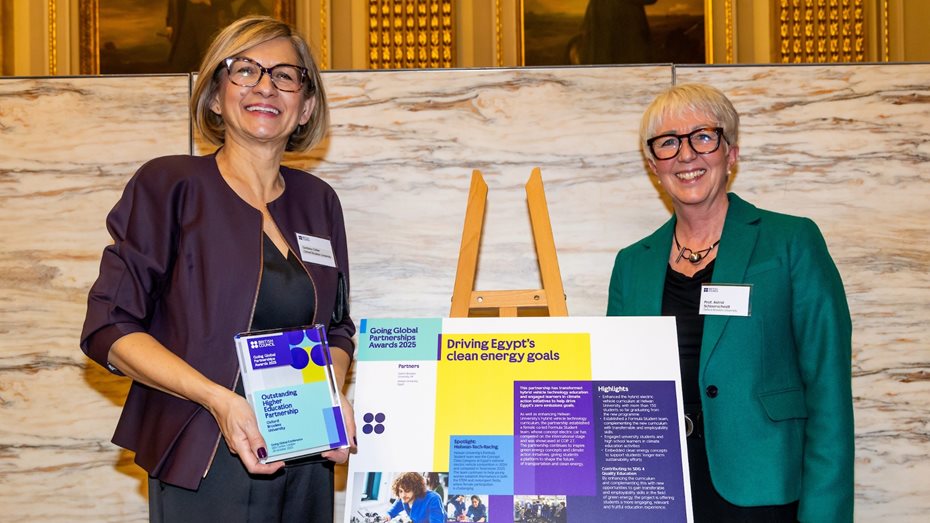 Two women at a stand, with an award