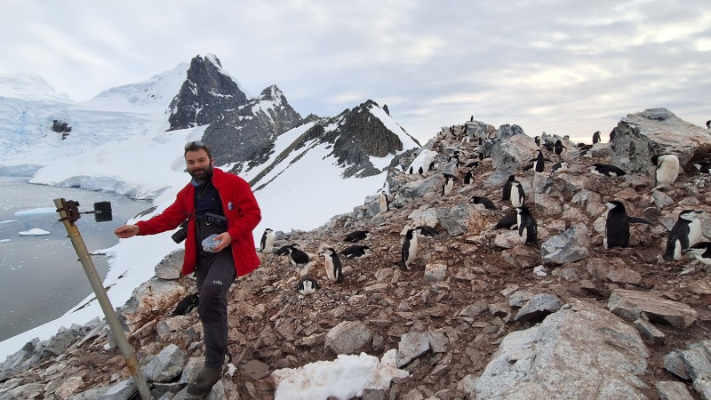 A man with a camera at a penguin colony in Antarctica