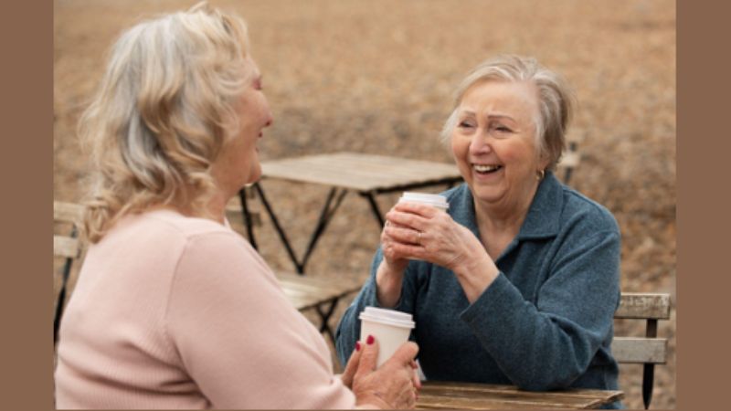 two elderly women having a cup of coffee/tea at a table