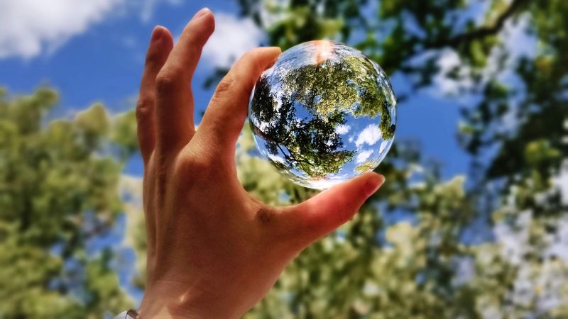 glass ball held up by a hand towards the sky