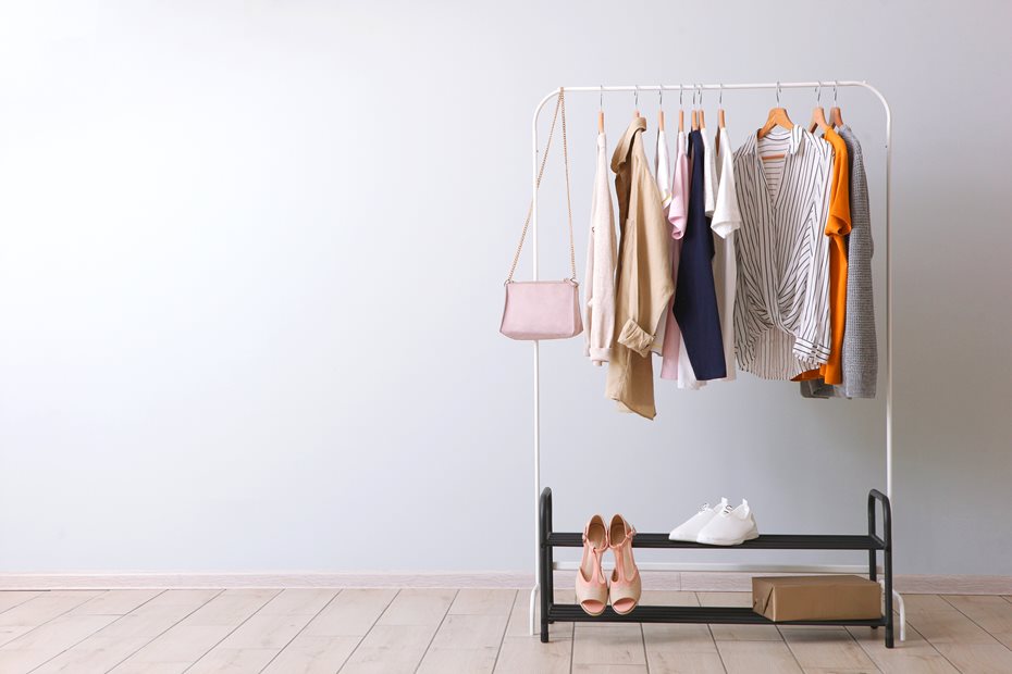 open wardrobe with clothes hanged on it with a shoestorage unit underneath