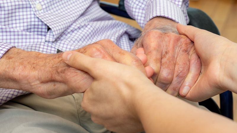 older person's hands holding the hands of a younger person