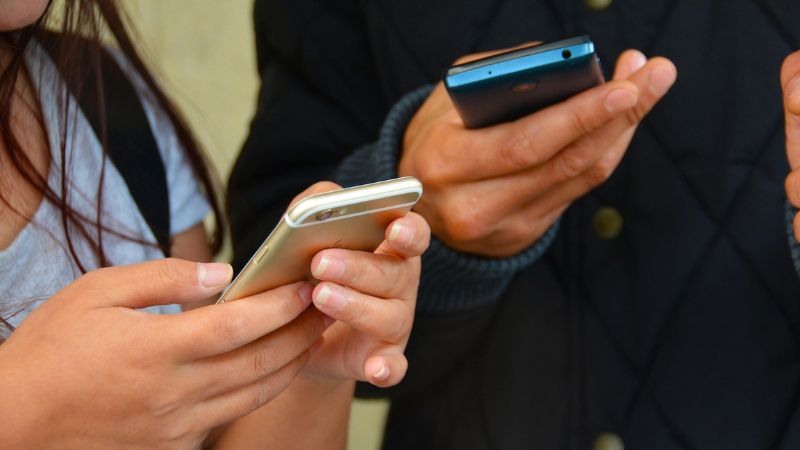 Close-up photograph of two people's hands holding mobile phones.