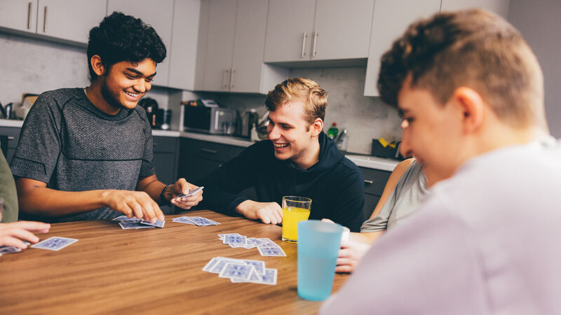 Students playing cards in a shared kitchen.