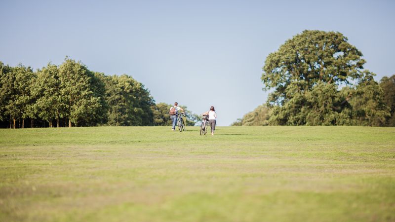 Two people pushing bikes in South Park, Oxford.