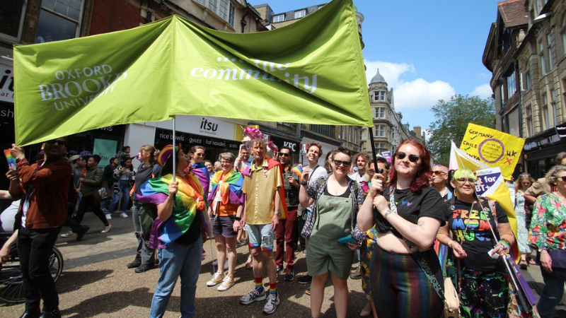 People holding the Oxford Brookes community banner at the Pride Parade.