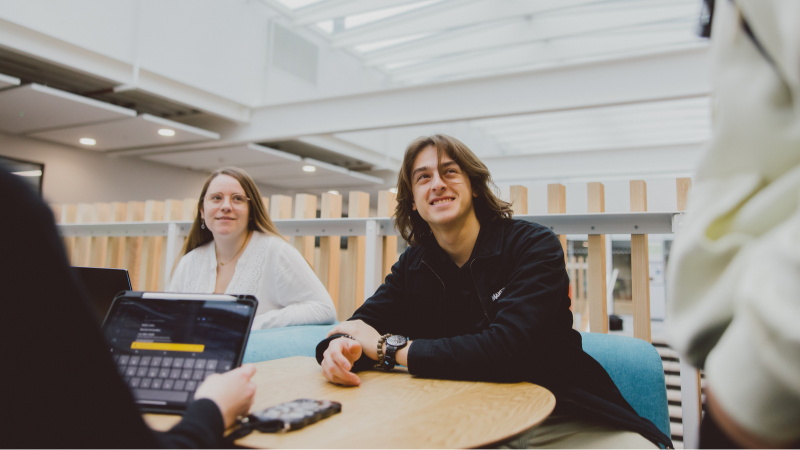 Students smiling during a conversation at a table.