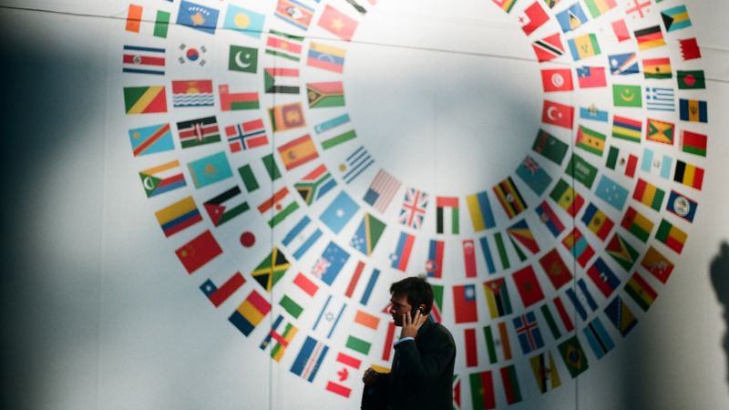 businessman on his phone in front of a circle made out of various country flags
